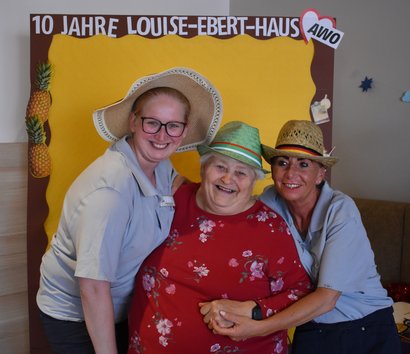 Drei Damen stehen vor einer Wand, darauf steht 10 Jahre Louise-Ebert-Haus