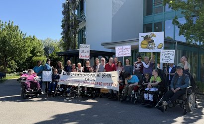 Eine Gruppe von Bewohnenden und Mitarbeitenden von leben und wohnen demonstriert mit Plakaten.