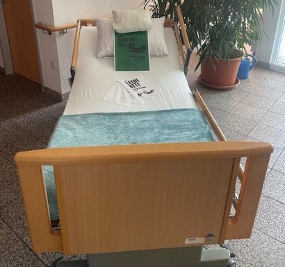 Leeres Pflegebett mit Protestbotschaft zur Pflegereform des Bundes. Motiv thematisiert fehlende Pflegekapazitäten.