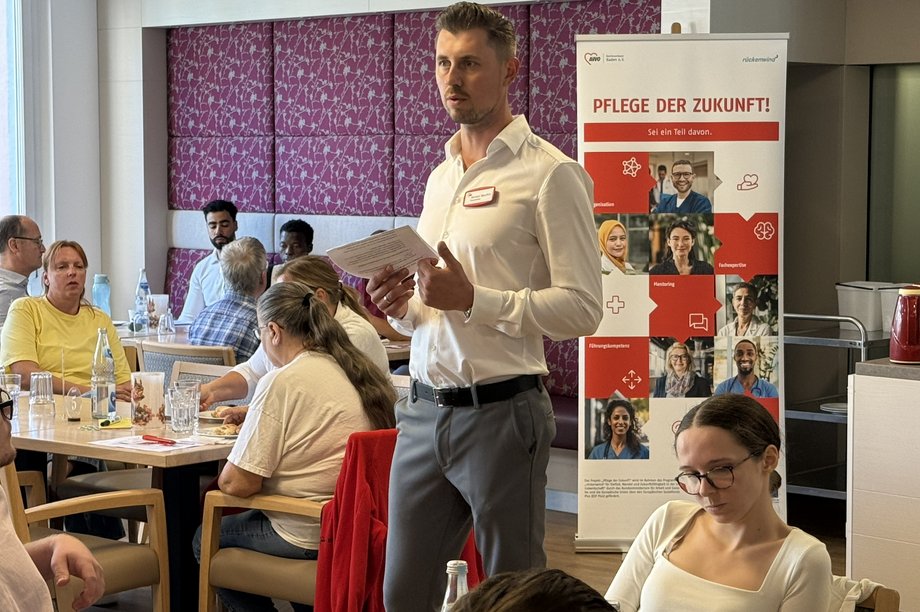 Informationsveranstaltung zur Kampagne „Pflege der Zukunft“: Eine Person stellt Inhalte vor, während Teilnehmende in einem Seminarraum zuhören und diskutieren