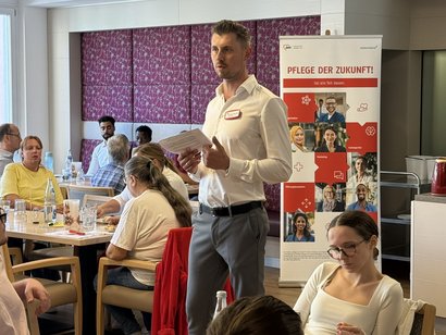 Informationsveranstaltung zur Kampagne „Pflege der Zukunft“: Eine Person stellt Inhalte vor, während Teilnehmende in einem Seminarraum zuhören und diskutieren